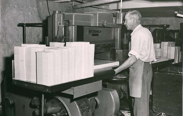 Historic photo of a man operating a printing press at CastlePierce.