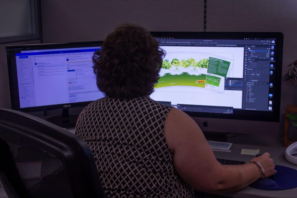 Castle Pierce employee designs packaging label on computer with dual monitor setup